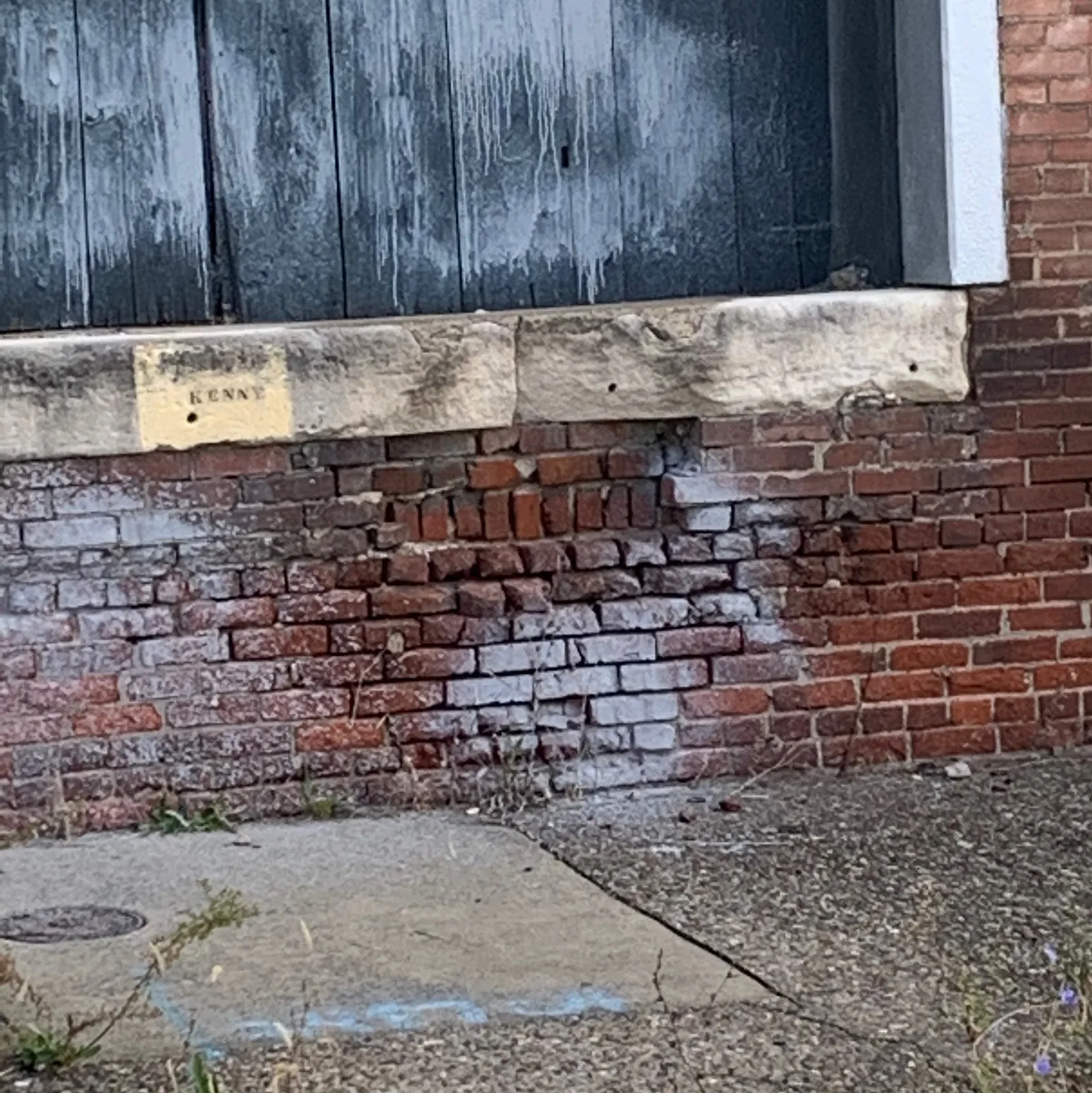 Weathered brick and stone foundation with heavy staining before surface preparation